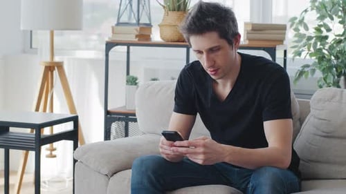 Young Man Using Smartphone While Relaxing on Couch