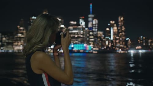 Young Woman Taking Photos of City at Night