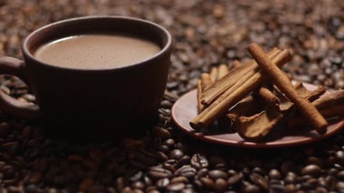Coffee Cup and Cinnamon Sticks on Coffee Beans
