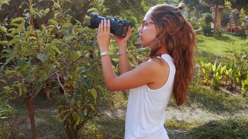 Woman Photographing Lush Greenery in Tropical Garden