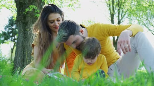 Happy Family Enjoying Tablet Outdoors in Springtime