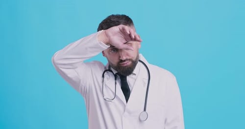 Studio Portrait of Tired Medical Doctor, Wiping Off Sweating Forehead
