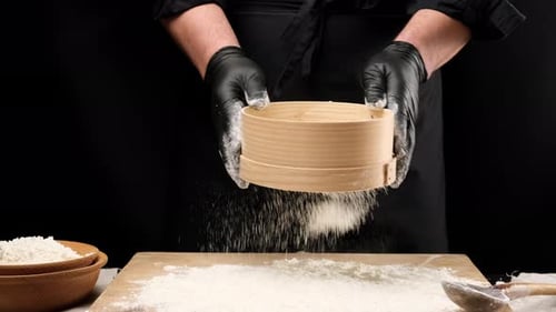 Person Sifts White Flour onto a Cutting Board