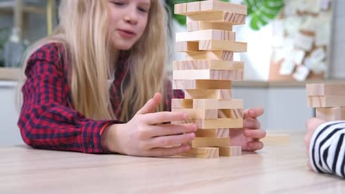 Children Playing Wooden Block Removal Tower Game at Home