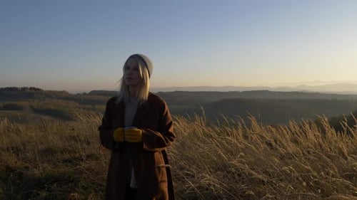 Woman Enjoying Golden Hour with a Warm Drink
