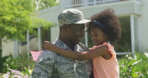 Soldier Hugs Adorable Child with American Flag