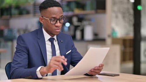 Focused African Businessman Reading Documents in Office