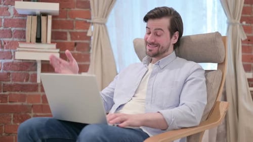 Man in Chair Video Calling on Laptop at Home