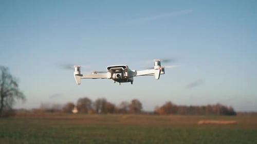 White Drone Hanging in Air or Flying on Nature Background. Slow Motion Shot.