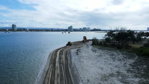 Enthüllende Drohnenansicht schwerer Maschinen, die an einem Strandsand für ein Küstenerosionsprojekt arbeiten. Pa