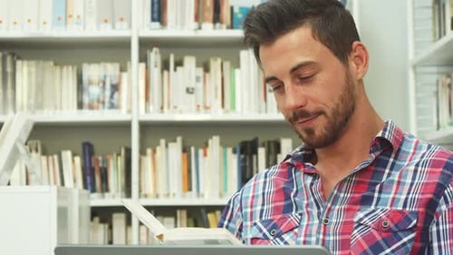 Young Man Reading Book in Library