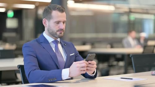 Geschäftsmann mittleren Alters nutzt Smartphone bei der Arbeit