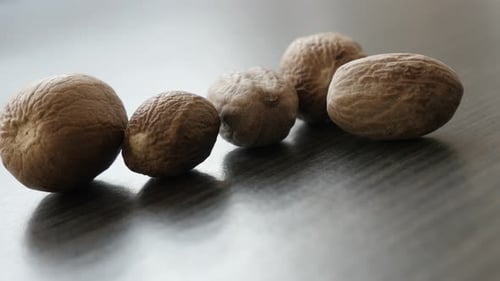 Surtido de especias de fruta con nuez moscada sobre mesa de madera, sartén lenta 4K 2160p, 30 fps, imágenes UltraHD - Myristica fra