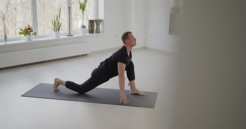 Man Stretching on Yoga Mat in Bright Studio