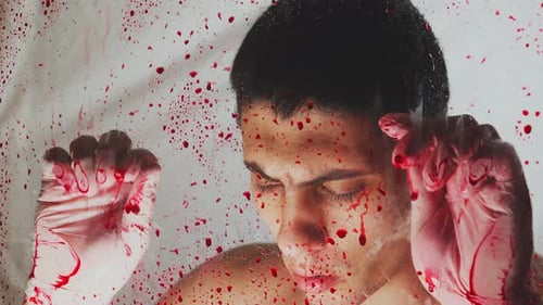 Un guapo asesino caucásico con guantes médicos cubiertos de sangre.