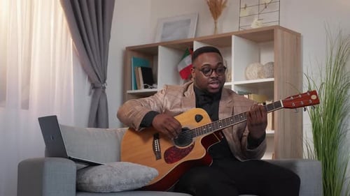 Man Teaching Guitar Online with Laptop