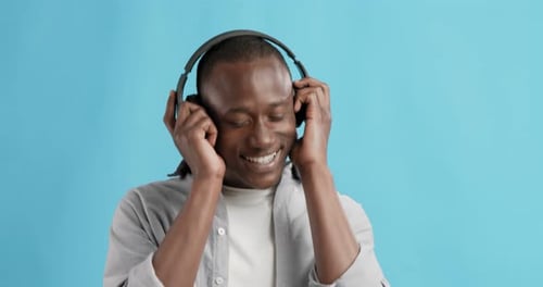 Man Enjoying Music with Headphones on Blue Background