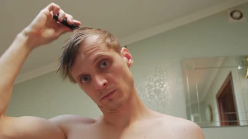 Man drying and combing wet hair in bathroom