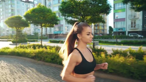 Muscular Woman Running in Morning City Streets.