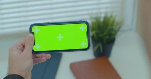Close Up of a Man Hand Holding a Mobile Telephone with a Vertical Green Screen in Chroma Key