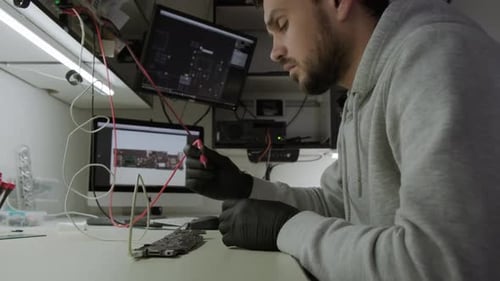 Electronic Renovation in Repair Shop Testing Electric Current in the Motherboard Using Multimeter