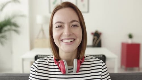 Woman Smiles with Headphones in Home Setting