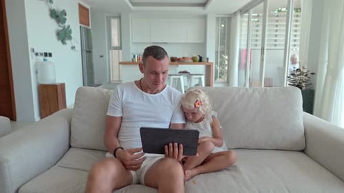Man and Child Relaxing at Home Using Tablet