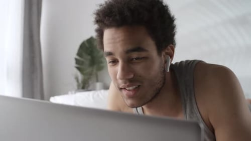 Man in Bed Talking on Laptop Video Call