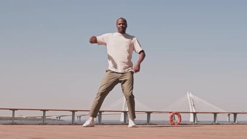 Young Black Man Dancing on Quay under Sky in Summer
