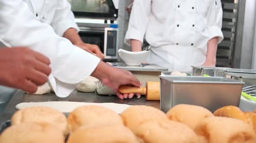 Chefs are preparing pastry dough, baking bakery food on a stainless steel table.