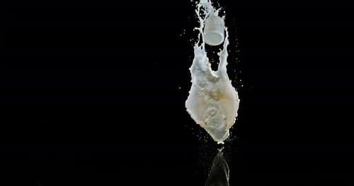 Vaso de leche rebotando y salpicando sobre fondo negro, cámara lenta 4K