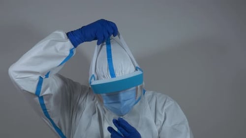 Person Putting on Face Shield with Protective Suit