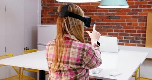 Woman Using VR Headset at Table Indoors