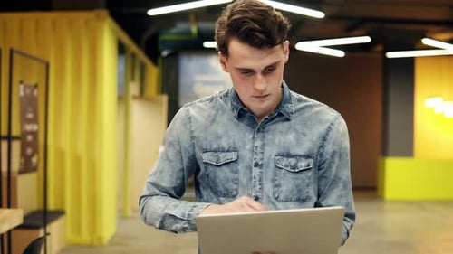 Young Man Working on Laptop in Modern Office