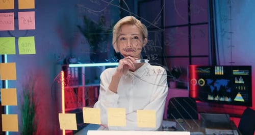 femme debout devant une planche de verre et écrivant dessus avait besoin de notes pour son projet d'entreprise