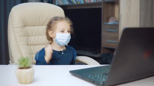 Child in Mask Waving at Laptop at Home