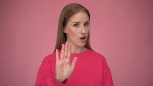 Woman Gesturing Stop Sign Against Pink Background