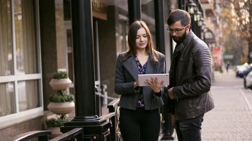 Woman and Man Look at Tablet Device Outside