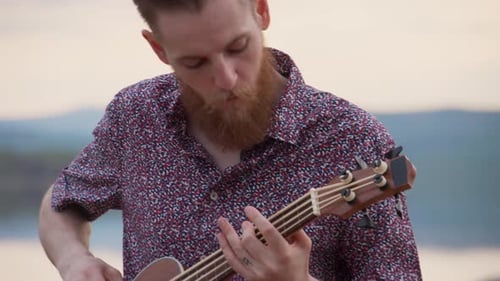 Man Playing Acoustic Bass Guitar by the Water