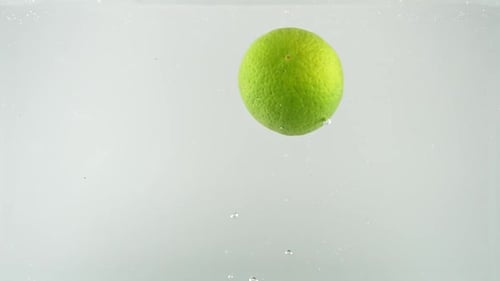 Limes Dropping into Water with Bubbles