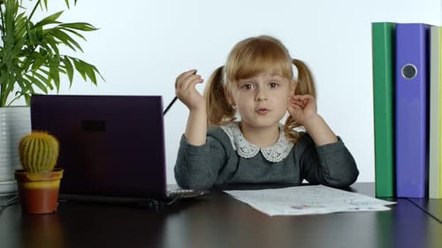 Child Sits at Desk Doing Homework