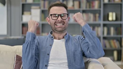 Excited Man Celebrates Success on Couch
