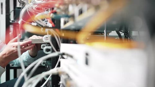 Sliding shot of a technician inserting a board into a fiber optic server