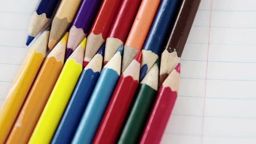 Lápices de colores dispuestos en patrón entrelazado sobre fondo blanco