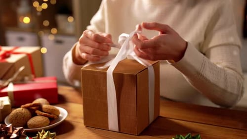 Woman Untying Christmas Ribbon On Box Close Up