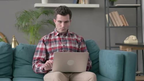 Man Celebrating Success Using Laptop on Couch