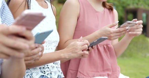 Young Adults Using Phones Together Outdoors