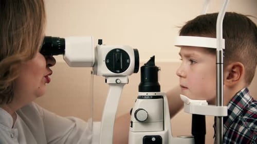 Boy Having a Treatment in Eye Clinic - a Woman Doctor Checking Little Boy's Eye Vision By Looking
