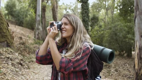 Happy Backpacker Girl with Camera Taking Pictures of Forest