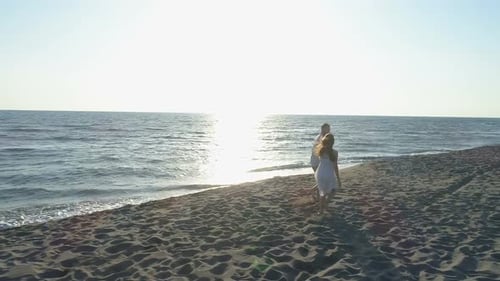 Aerial View of Couple Having Fun Running Along the Beach Near the Water